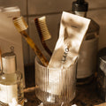 Close-up of our Naturally Whitening Toothpaste squeezed tube and two toothbrushes in a glass on a bathroom sink setting.